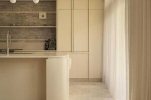 Moderní kuchyně v rodinném domě s oblým ostrůvkem, světlými povrchy a minimalistickým řešením