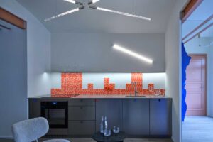 Kuchyň v rekonstruovaném bytě s moderními prvky barevným obkladem a kontrastem historické dispozice a současného designu