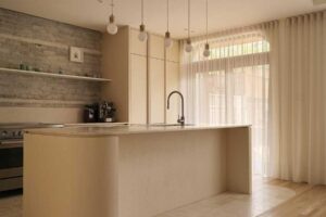 Boční pohled na kuchyňský ostrůvek s oblými hranami a propojením kamenné a dřevěné podlahy