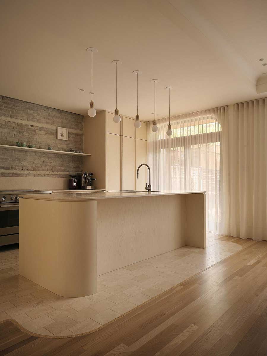 Boční pohled na kuchyňský ostrůvek s oblými hranami a propojením kamenné a dřevěné podlahy