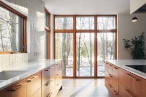 Kuchyň s minimalistickou linkou a ostrůvkem propojuje přírodní dřevo s čistými liniemi modernismu