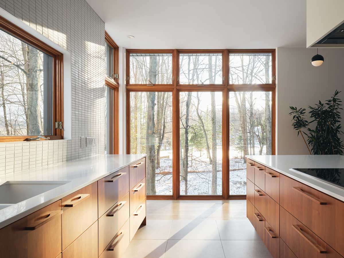 Kuchyň s minimalistickou linkou a ostrůvkem propojuje přírodní dřevo s čistými liniemi modernismu