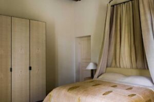 Ložnice s baldachýnem, textilními závěsy a viditelnými dřevěnými trámy