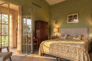 Stylová ložnice ve vile Brigitte Bardot s přírodními barvami textiliemi a výhledem do zahrady.