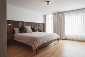 Detail postele s dřevěným obkladem stěny navazuje na modernistickou estetiku domu