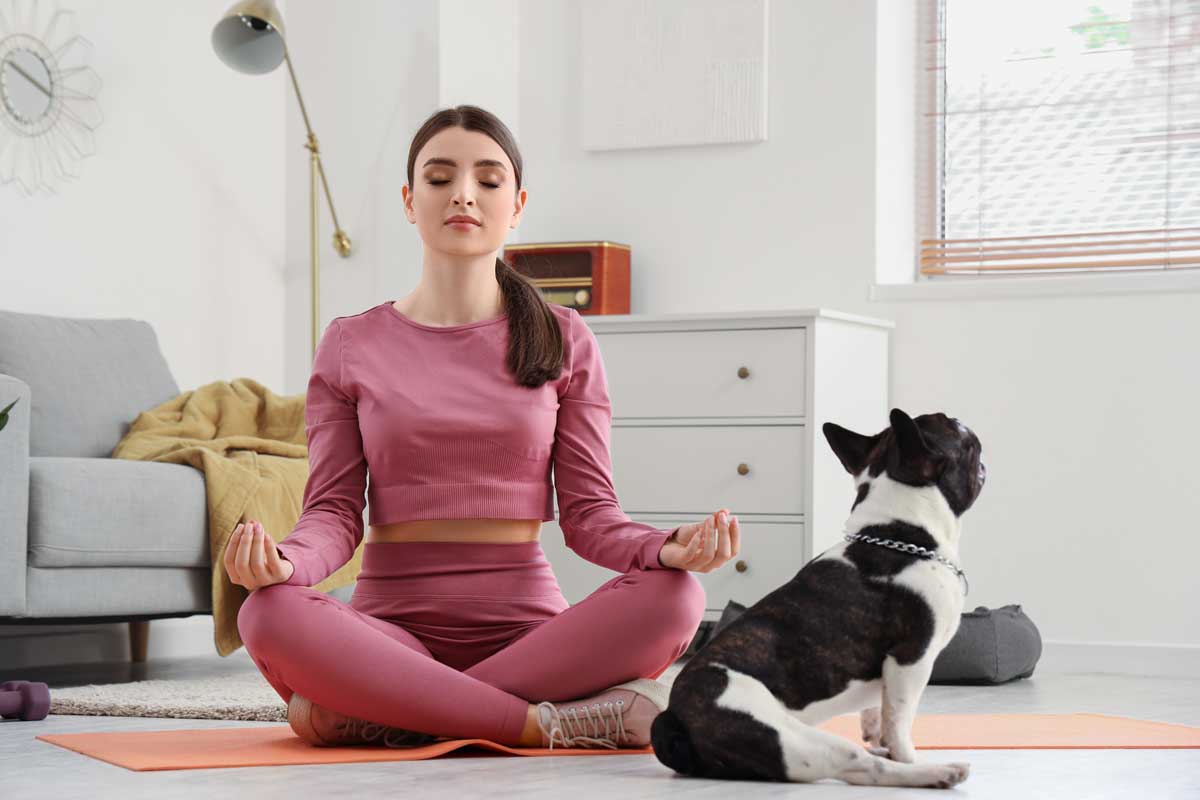 Žena cvičí jógu a medituje doma na podložce v obývacím pokoji
