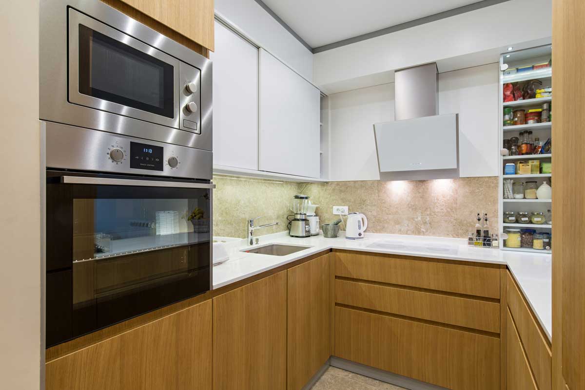 Moderní kuchyně s vestavnou troubou a mikrovlnnou troubou z nerezu, na kterých jsou viditelné otisky prstů a šmouhy od rukou.