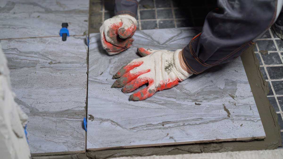 Usazování nové dlažby na starý obklad s použitím vymezovacích klipsů pro rovné spáry a přesnou rovinu