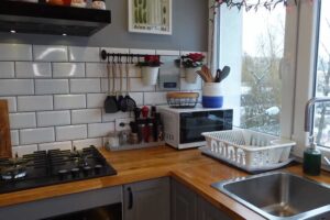 Zrekonstruovaná paneláková kuchyně s dřevěnou pracovní deskou a bílými obklady