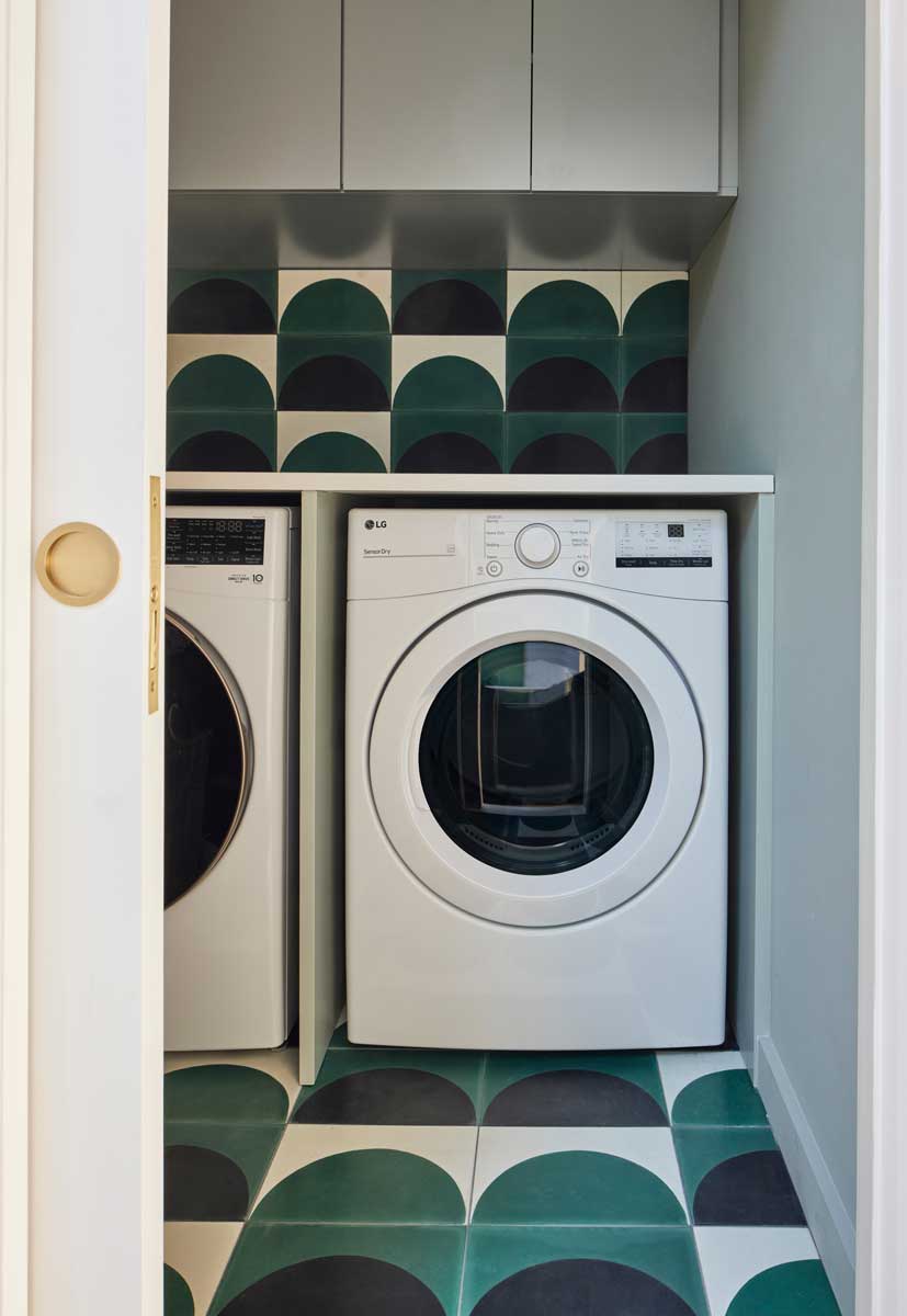 Prádelna s dekorativním obkladem v zelených tónech a vestavěnými spotřebiči