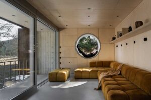 Obývací prostor ve stodole s velkým prosklením kruhovým oknem a modulovou pohovkou
