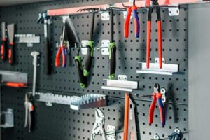 Detail organizace nářadí na perforované kovové stěně v garáži s vestavěným pracovním zázemím.