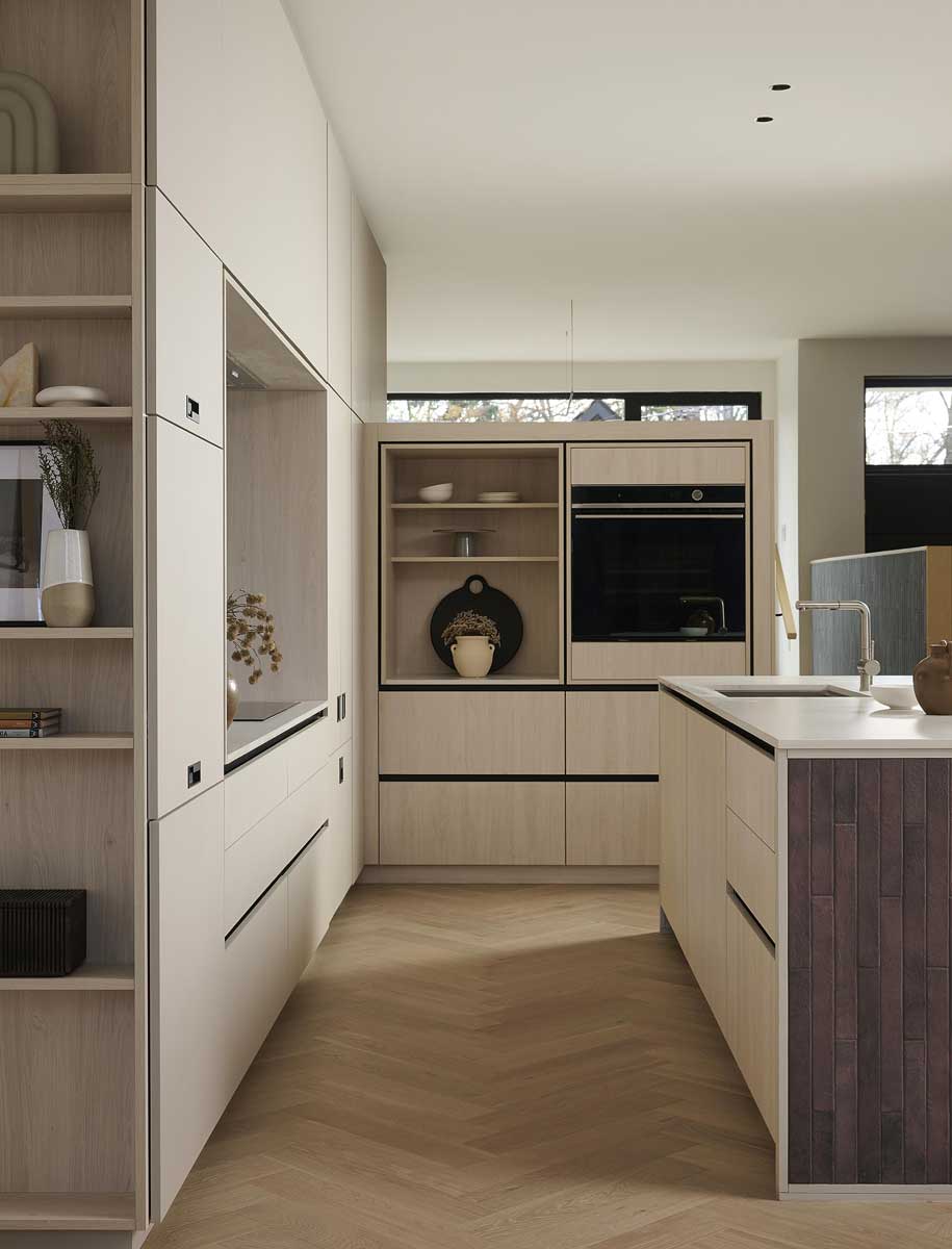 Otevřená kuchyně s vestavnými skříněmi z dubu a minimalistickým ostrůvkem propojená s obytným prostorem