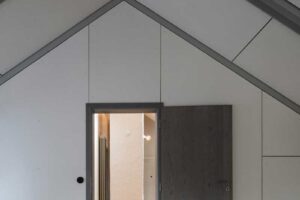 Detail podkroví s dřevěnými parketami šikmým stropem a vestavěnými dveřmi