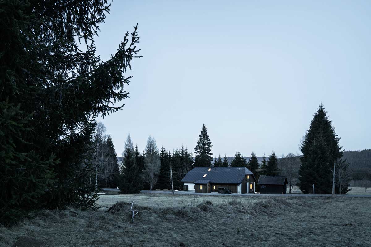 Pohled na šumavskou chalupu a stodolu v otevřené krajině při soumraku