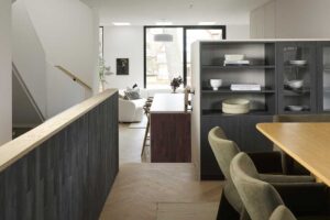 Pohled z jídelny do otevřeného obytného prostoru s kuchyní, schodištěm a světlíky