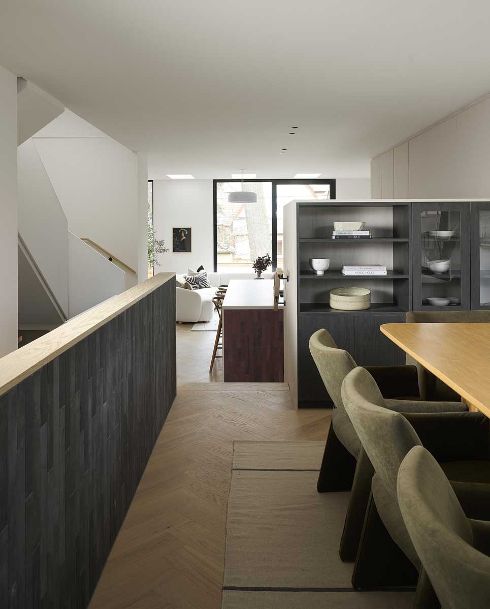 Pohled z jídelny do otevřeného obytného prostoru s kuchyní, schodištěm a světlíky