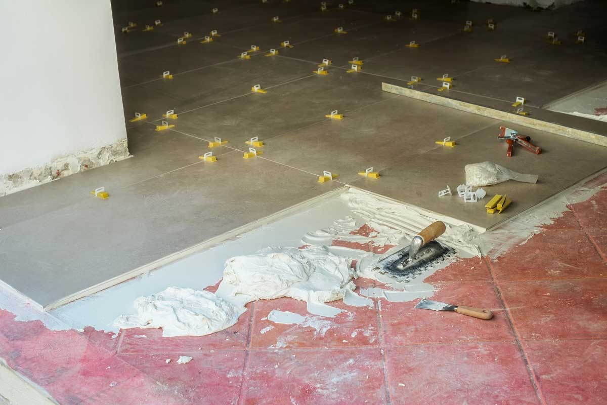 Pokládka nové dlažby na staré kachličky pomocí flexibilního lepidla a nivelačních klipsů bez nutnosti bourání