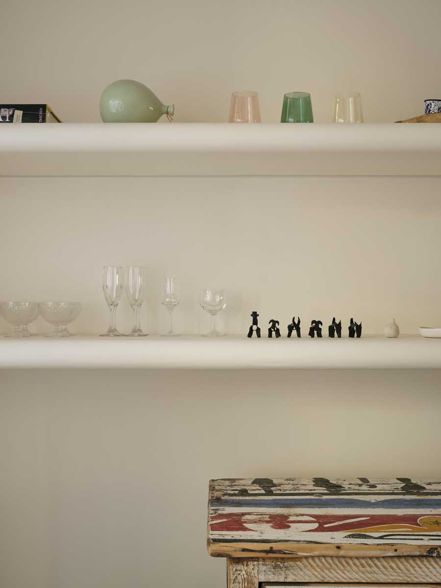 Otevřená police s keramikou a drobnými dekoracemi v obytném prostoru rodinného domu