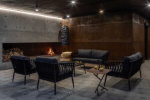 Posezení u krbu v betonovém suterénu s ocelovými stěnami