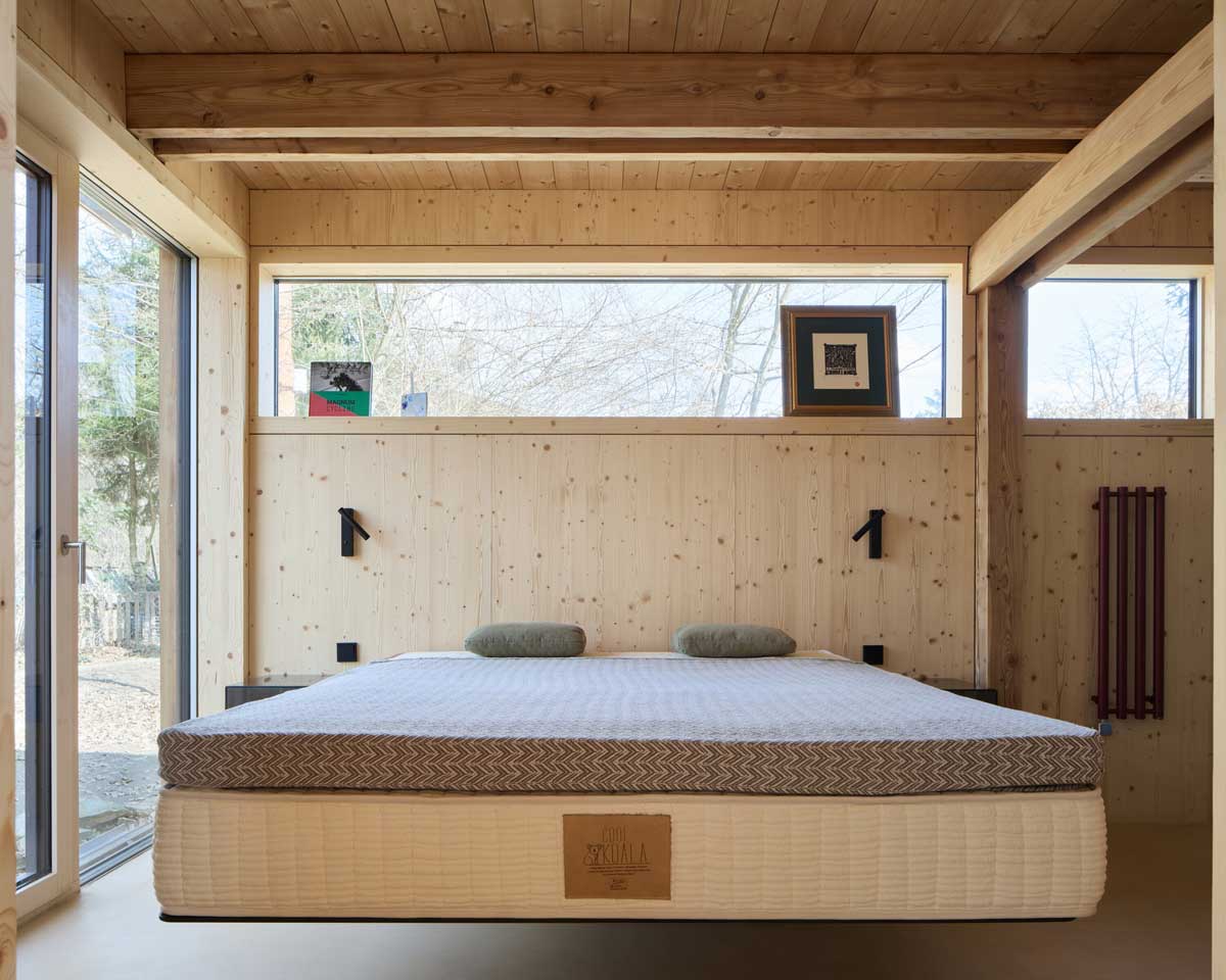 Ložnice v přístavbě Domu Medník s jednoduchým dřevěným interiérem