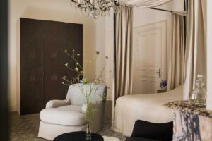 Postel s baldachýnem, historickým lustrem a vzorovanými textiliemi