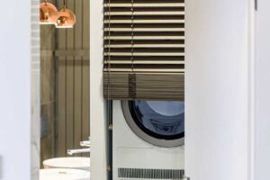 Vestavěná pračka a sušička skryté ve skříni v koupelně s důrazem na čistotu a kompaktní řešení.