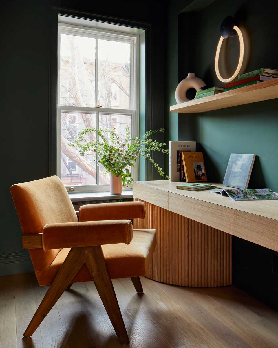 Pracovní kout s dřevěným stolem, pohodlným křeslem a zelenými stěnami