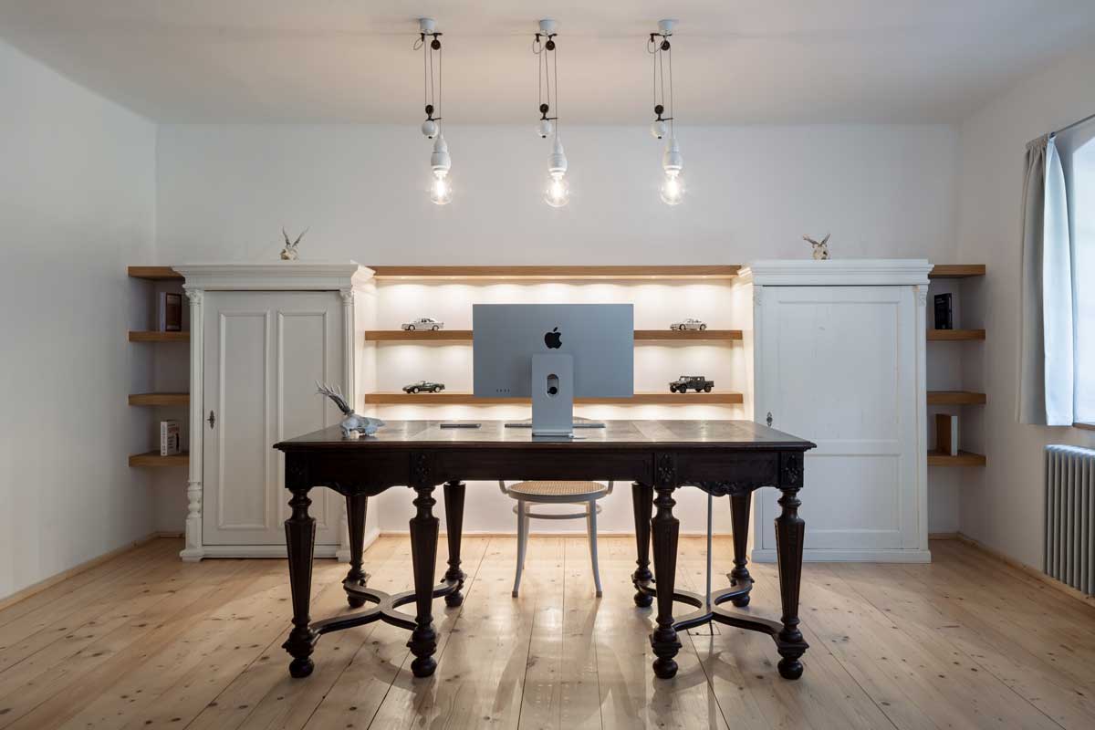 Pracovna v chalupě s historickým stolem vestavěnými policemi a měkkým osvětlením