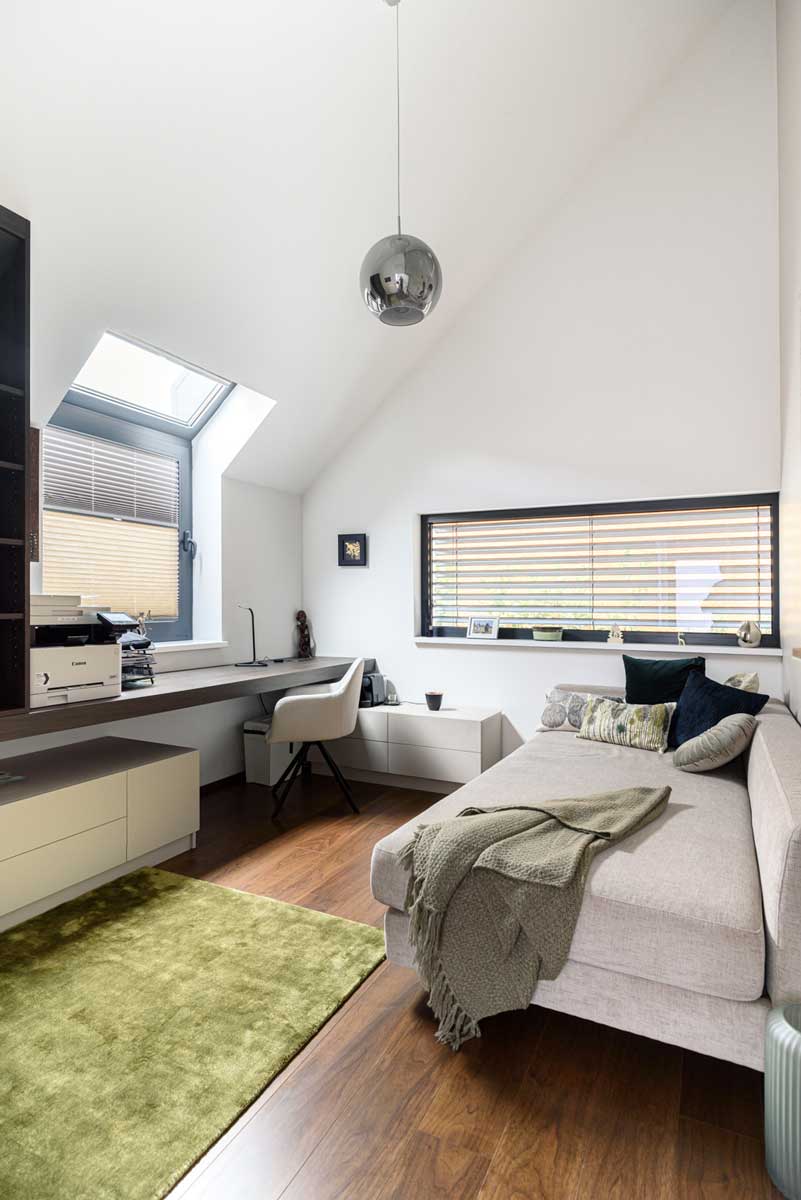 Pracovní stůl pod oknem s jednoduchým nábytkem na míru a dostatkem denního světla.