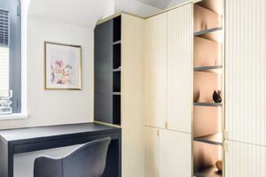 Pracovní kout s vestavěným stolem a vitrínovou skříní s jemným podsvícením.