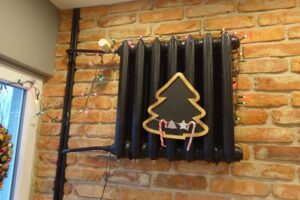 Radiátor po rekonstrukci natřený tmavou barvou na cihlové stěně