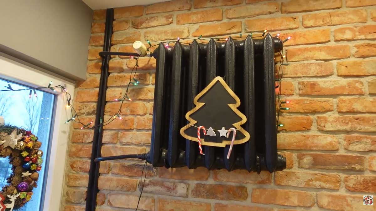 Radiátor po rekonstrukci natřený tmavou barvou na cihlové stěně