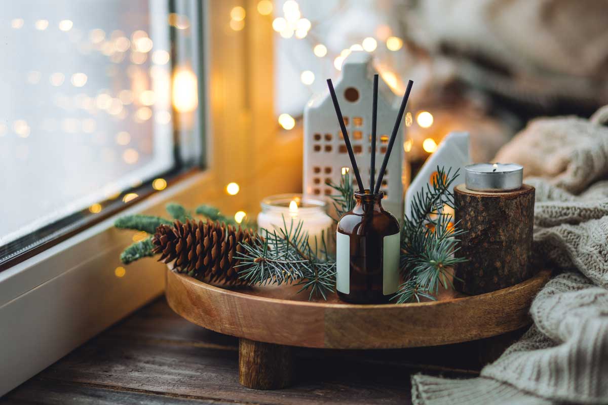 Jednoduché zimní aranžmá z přírodních materiálů se svíčkou a větvičkami u okna