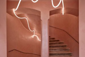 Schodišťový prostor s klenbami pudrovou omítkou a liniovým svítidlem v historickém bytovém domě