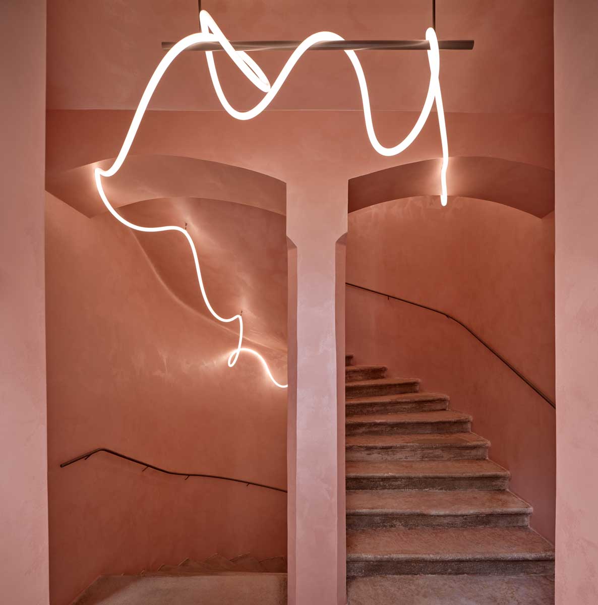 Schodišťový prostor s klenbami pudrovou omítkou a liniovým svítidlem v historickém bytovém domě