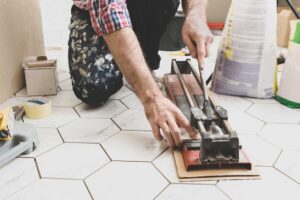 Řezání keramické dlažby ruční řezačkou při obkladačských pracích