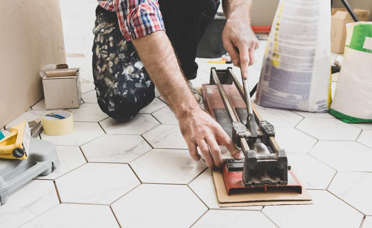 Řezání keramické dlažby ruční řezačkou při obkladačských pracích