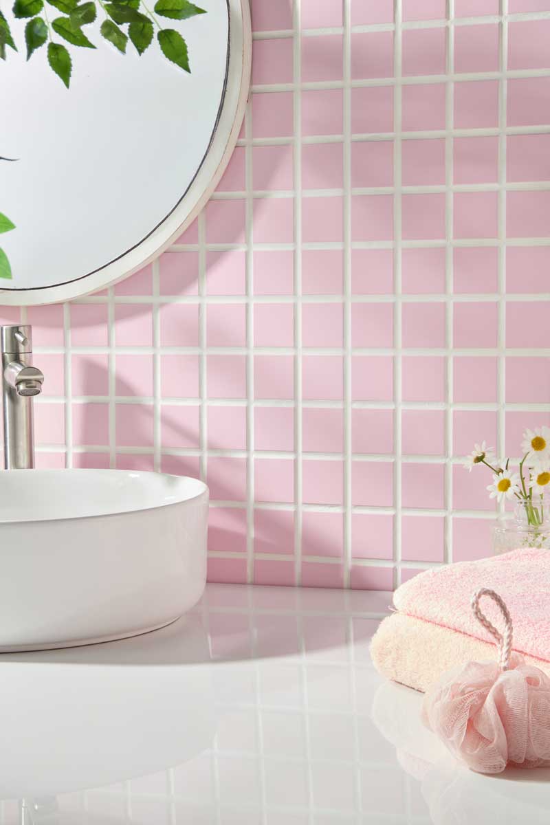 Detail růžového keramického obkladu v koupelně s umyvadlem a doplňky