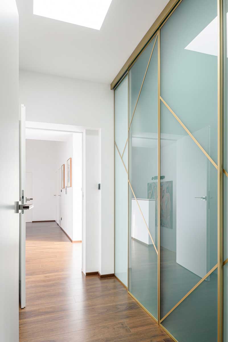 Vestavěná šatní skříň s otevřeným sezením a integrovaným osvětlením v předsíni.