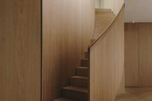 Schodiště z masivního dřeva s plynulými křivkami jako výrazný architektonický prvek interiéru
