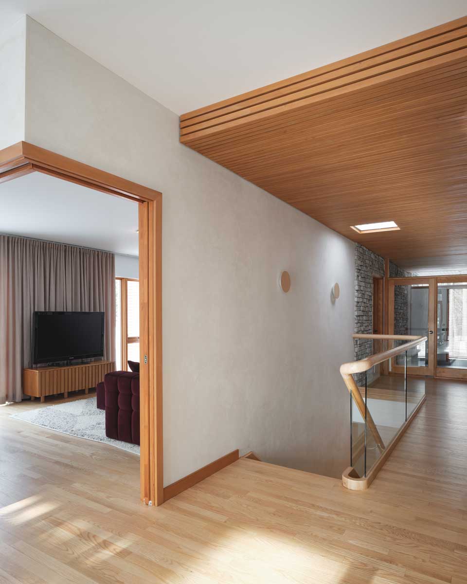 Schodiště s dřevěným obkladem a subtilním zábradlím podtrhuje architektonickou čistotu domu.