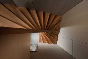 Dřevěné schodiště s vějířovitými stupni v moderní vestavbě