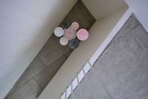 Detail schodiště s původními kamennými stupni a atypickým svítidlem ve sdílených prostorách domu