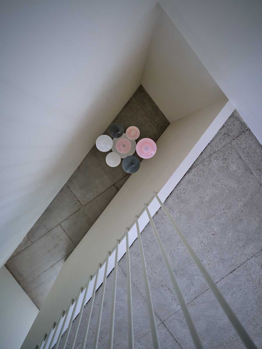 Detail schodiště s původními kamennými stupni a atypickým svítidlem ve sdílených prostorách domu