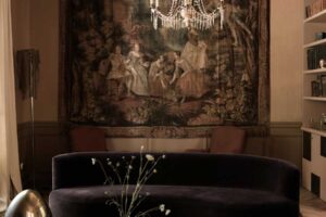 Společenská zóna s tmavou sedačkou, tapiserií a křišťálovým lustrem