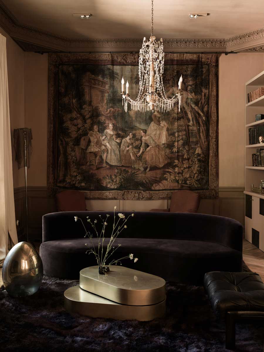 Společenská zóna s tmavou sedačkou, tapiserií a křišťálovým lustrem