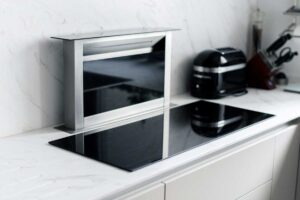 Indukční varná deska s integrovaným výsuvným odsavačem par zapuštěná do světlé pracovní desky.