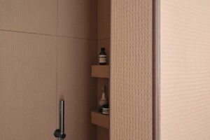 Detail sprchového koutu s keramickým obkladem a integrovanými policemi
