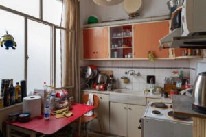 Stará kuchyň s původními skříňkami a spotřebiči před renovací